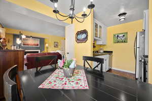 Dining room with sink, an inviting chandelier, dark hardwood flooring, and a textured ceiling