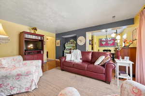 Living room with a textured ceiling and hardwood flooring with dining room in background