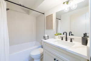 Full bathroom with toilet, shower / tub combo with curtain, and vanity