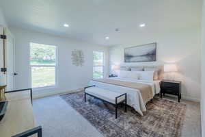 Carpeted bedroom featuring multiple windows and a textured ceiling