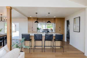 Kitchen featuring a kitchen bar, light hardwood / wood-style flooring, a notable chandelier, and decorative light fixtures