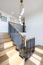 Stairway with wood-type flooring and a notable chandelier