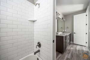 Bathroom 4 -  with tiled shower / bath combo, vanity, and hardwood / wood-style flooring