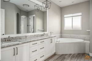 Master Bathroom (2)  featuring wood-type flooring, tiled tub, and vanity