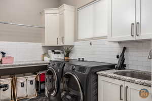 Clothes washing area featuring cabinets, sink, and independent washer and dryer