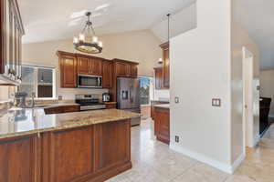 Kitchen featuring stainless steel appliances, an inviting chandelier, sink, light stone countertops, and vaulted ceiling, 1/2 bath