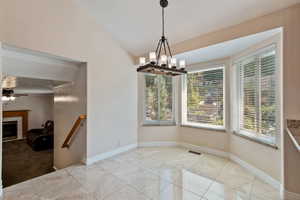 dining area with ceiling fan with notable chandelier, a tile fireplace, and light tile patterned flooring, new windows in this room.