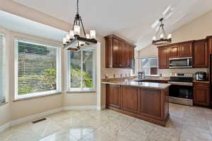 Kitchen featuring lofted ceiling, appliances with stainless steel finishes, plenty of natural light, and a notable chandelier