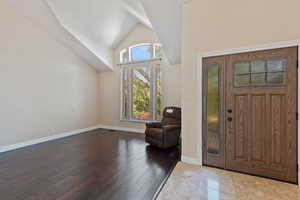 Foyer entrance with high vaulted ceiling and hardwood / wood-style floors