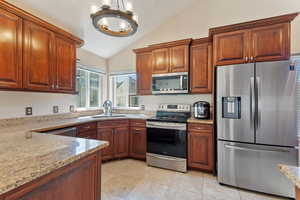 Kitchen featuring an inviting chandelier, stainless steel appliances, sink, lofted ceiling, and light stone counters