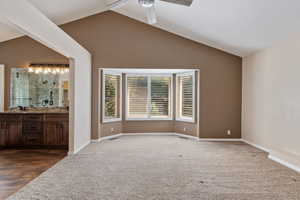 Large Primary Bedroom featuring vaulted ceiling, ceiling fan plantation shutters, double sinks in bath, walk in shower