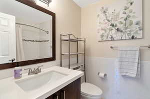 Shared Bathroom with vanity, toilet, tile walls, and walk in shower