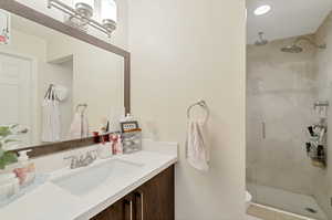 Bathroom with vanity, a shower with shower door, and toilet