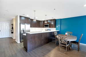 Kitchen with hardwood / wood-style flooring, kitchen peninsula, stainless steel appliances, and dark brown cabinetry