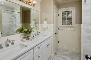 Bathroom featuring vanity, tiled shower, and tile patterned flooring