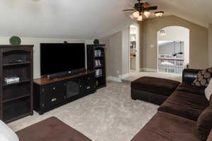 Carpeted living room featuring ceiling fan, a textured ceiling, and vaulted ceiling