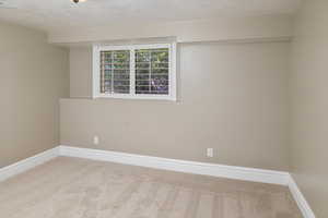 Unfurnished room with a textured ceiling and carpet