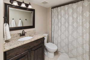 Bathroom featuring tile patterned flooring, toilet, a textured ceiling, and vanity