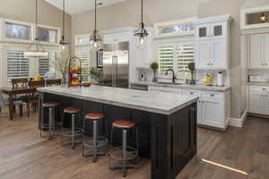 Kitchen with dark wood-type flooring, stainless steel built in fridge, white cabinetry, and sink