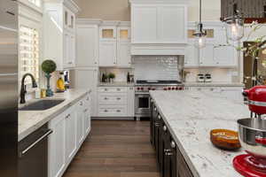 Kitchen with dark hardwood / wood-style floors, appliances with stainless steel finishes, hanging light fixtures, sink, and white cabinetry