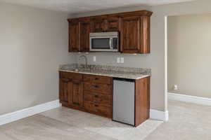 Kitchen featuring a textured ceiling, light stone countertops, light carpet, appliances with stainless steel finishes, and sink