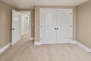 Unfurnished bedroom with light colored carpet and a closet