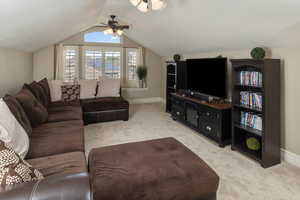 Living room with lofted ceiling, ceiling fan, and light carpet