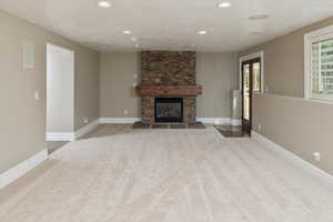 Unfurnished living room featuring carpet flooring, a fireplace, and a textured ceiling