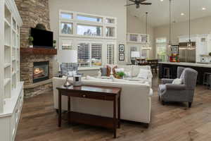 Living room featuring dark wood-type flooring, ceiling fan, a wealth of natural light, and a fireplace