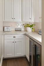 Interior space with decorative backsplash, white cabinetry, dark hardwood / wood-style flooring, and wine cooler