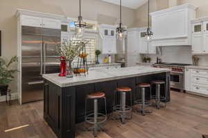 Kitchen with dark wood-type flooring, white cabinetry, and premium appliances