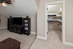 Interior space with ceiling fan, vaulted ceiling, and carpet floors