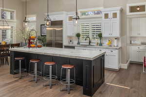 Kitchen with white cabinets, hanging light fixtures, dark hardwood / wood-style flooring, sink, and stainless steel built in refrigerator