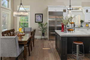 Kitchen with a wealth of natural light, hardwood / wood-style floors, white cabinetry, and built in refrigerator