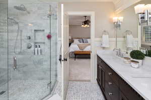 Master bathroom featuring vanity, a shower with shower door, and ceiling fan