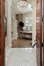 Foyer entrance featuring a fireplace, lofted ceiling, ornate columns, and light hardwood / wood-style floors