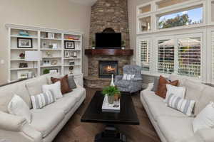 Living room with dark wood-type flooring and a stone fireplace