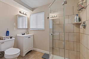 Bathroom with vanity, toilet, tile patterned floors, and walk in shower