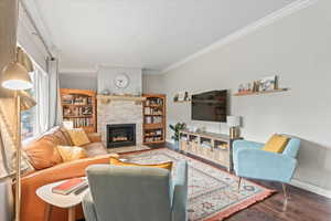 Living room featuring a fireplace, dark hardwood / wood-style floors, and crown molding