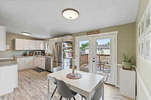 Kitchen with white cabinetry, light hardwood / wood-style flooring, stainless steel appliances, and sink