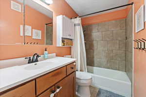 Full bathroom with vanity, toilet, tile patterned floors, and shower / bath combo with shower curtain