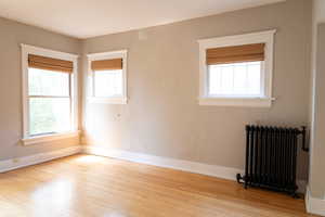 Empty room with a healthy amount of sunlight, radiator, and light hardwood / wood-style floors