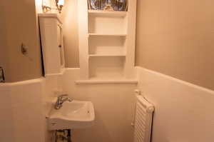 Bathroom featuring tile walls, radiator, and sink