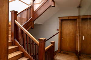 Staircase with lofted ceiling and wood-type flooring