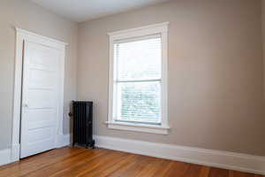 Spare room featuring radiator heating unit and wood-type flooring