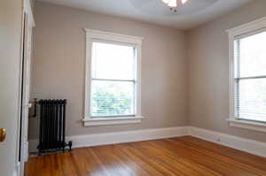 Unfurnished room featuring radiator heating unit, hardwood / wood-style flooring, and ceiling fan