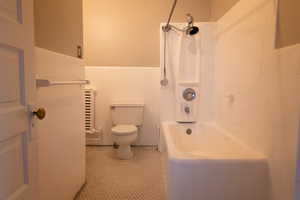 Bathroom featuring tile walls, toilet, bathtub / shower combination, and tile patterned floors