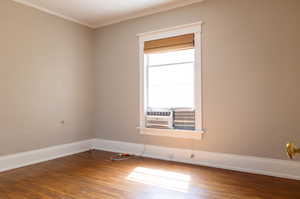 Spare room with cooling unit, crown molding, and hardwood / wood-style flooring