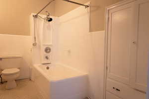 Bathroom featuring tile walls, toilet, tiled shower / bath combo, and tile patterned floors