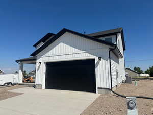 View of side of home featuring an outdoor structure, a garage, and central AC unit